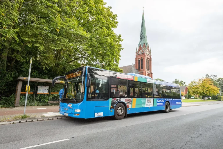 Blauer Bus der Stadtwerke WHV an Haltestelle Banter Kirche
