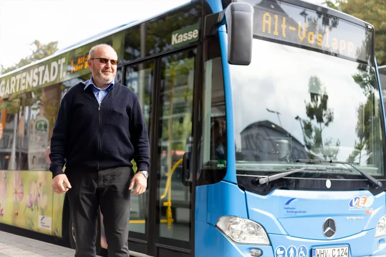 Ein Busfahrer der Stadtwerke Wilhelmshaven steht vor einem blauen Bus