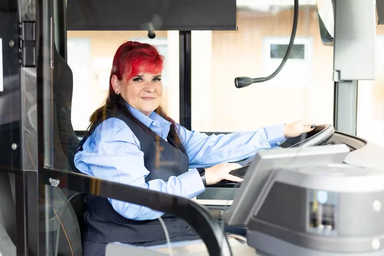 Mitarbeiterin Busfahrerin sitzt am Lenkrad eines Busses